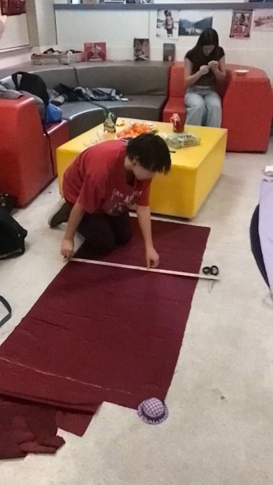 A person measuring a red carpet
Description automatically generated