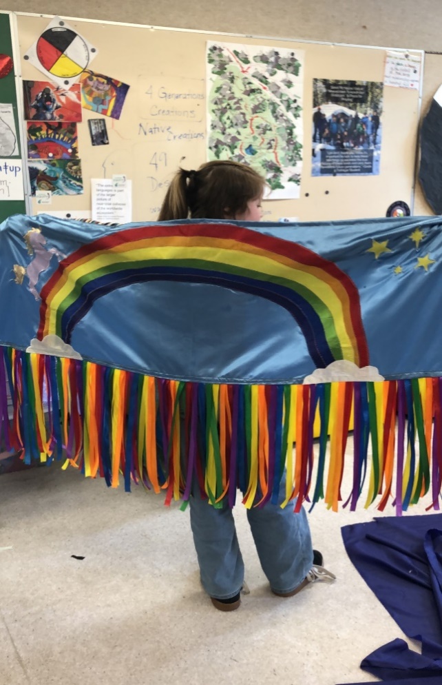 A person holding a rainbow flag
Description automatically generated