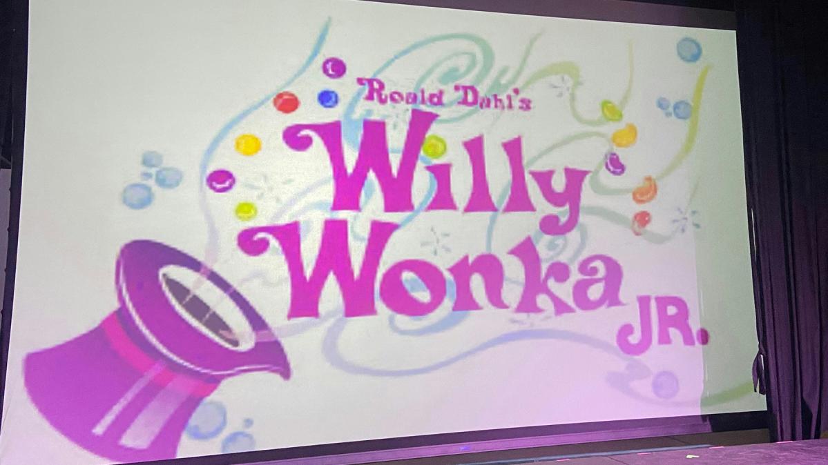 Poster for the play, Willy Wonka Jr. showing a purple top hat and scrolly text.